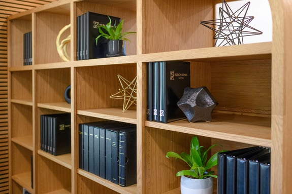 A shelf with plants and black binders on it. 